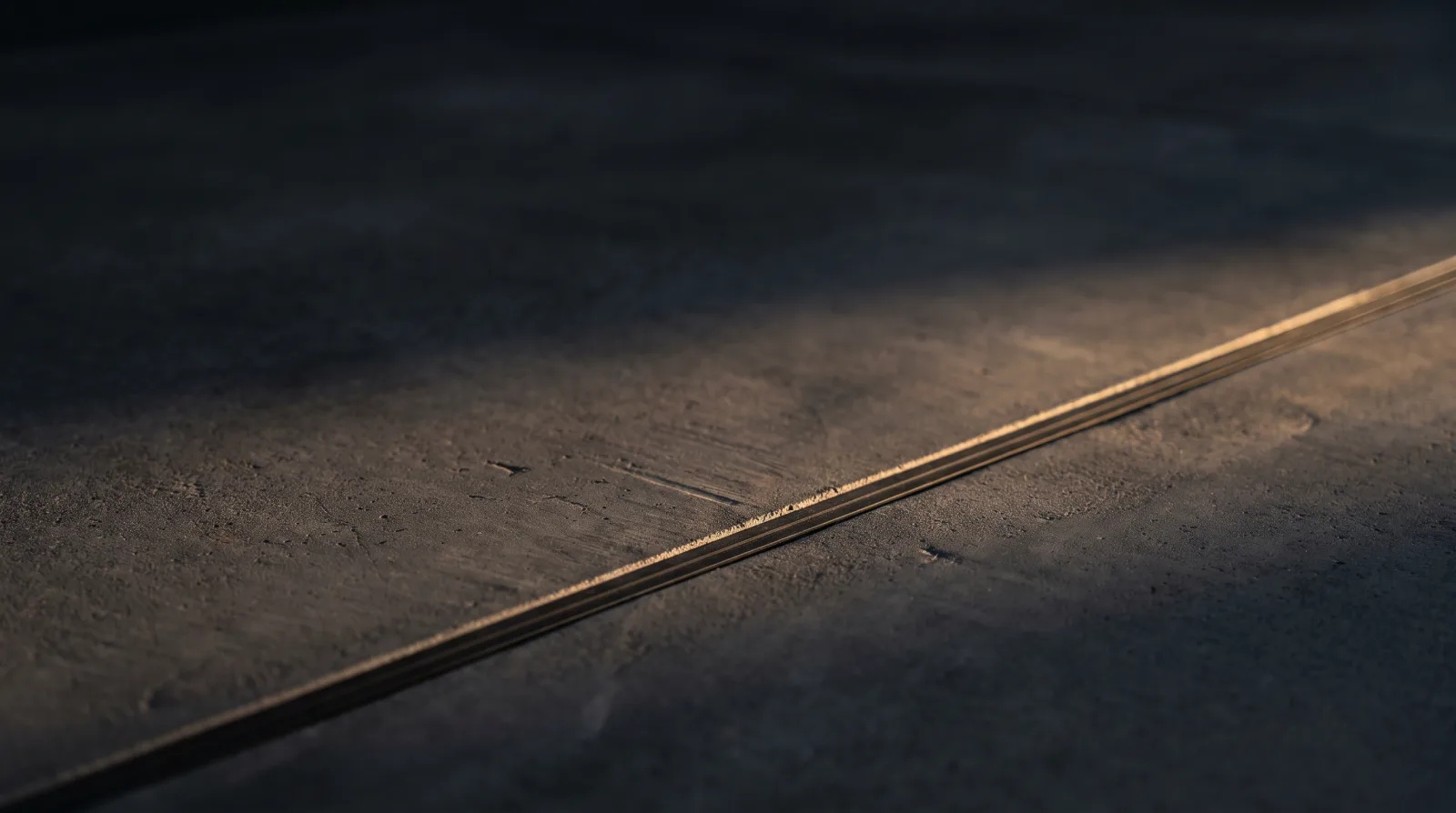 Close-up of a concrete expansion joint line catching warm evening light