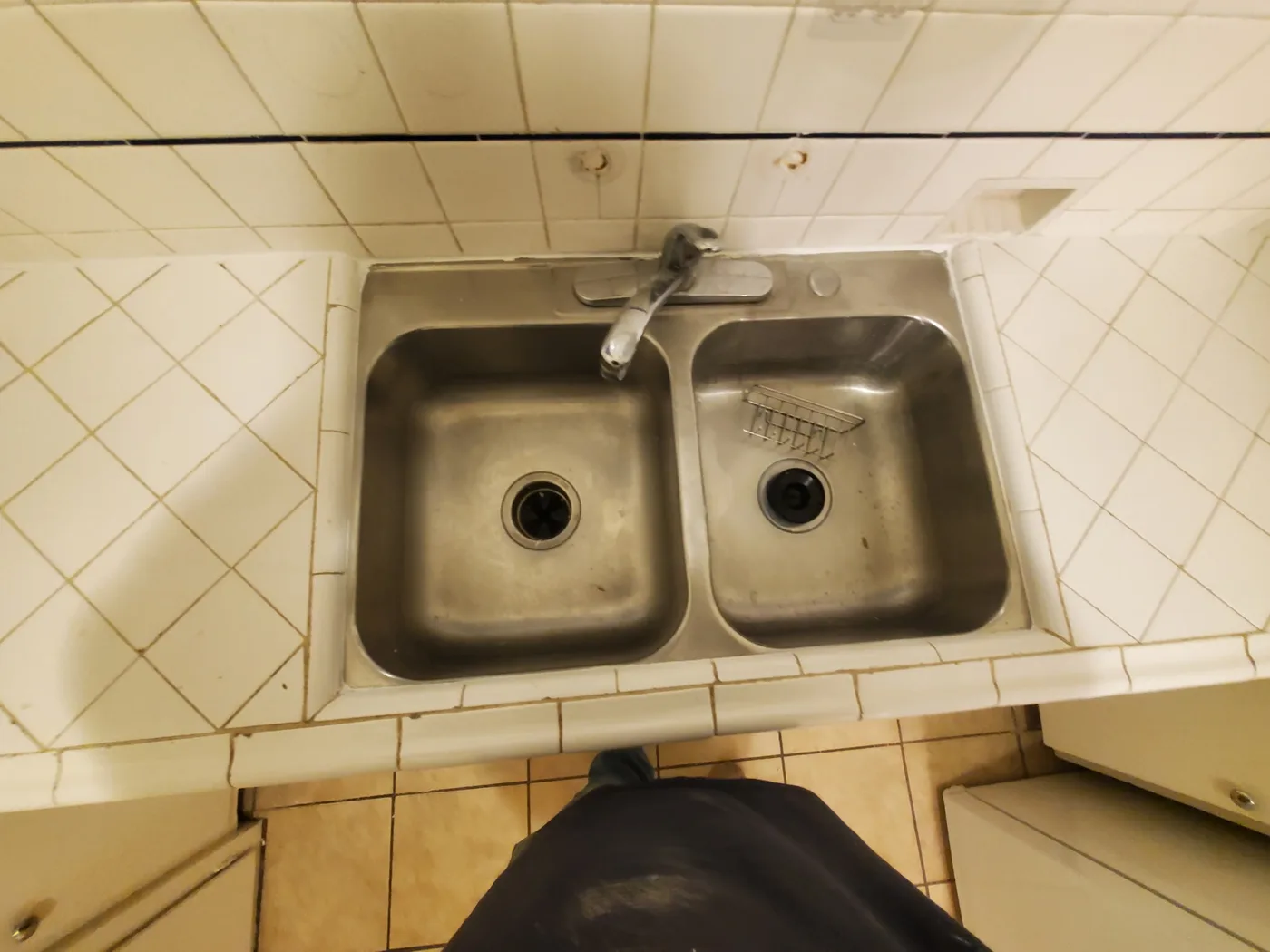 Before: Dated kitchen sink surrounded by aging tan wall tile