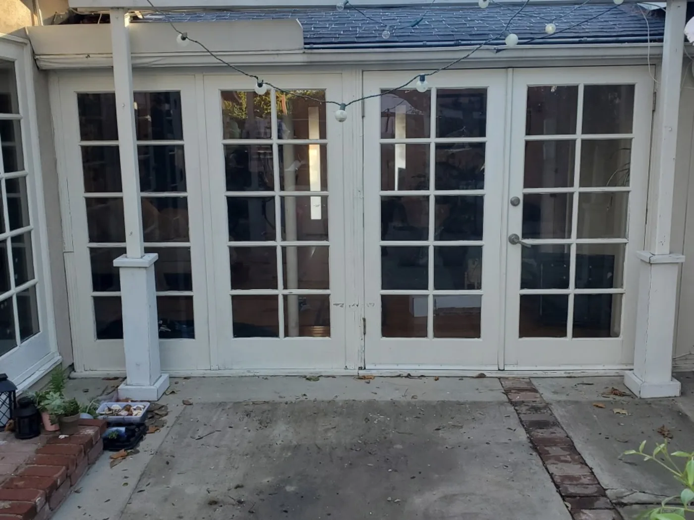 Before: Rear patio with stained concrete and weathered French doors
