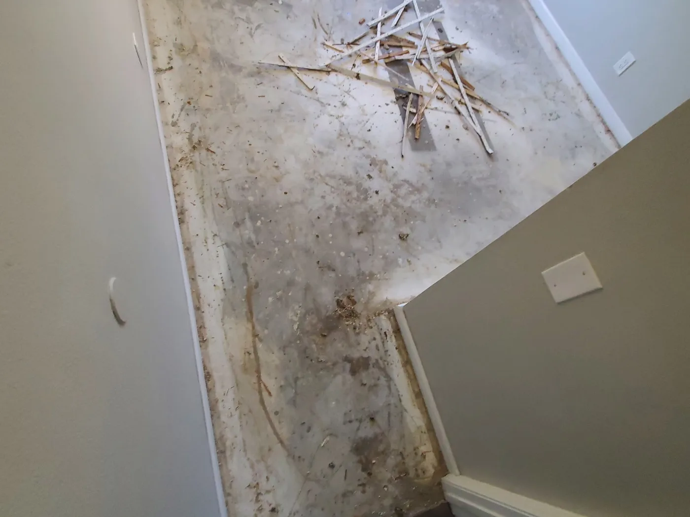 Before: Stair landing with a stained, damaged floor and debris